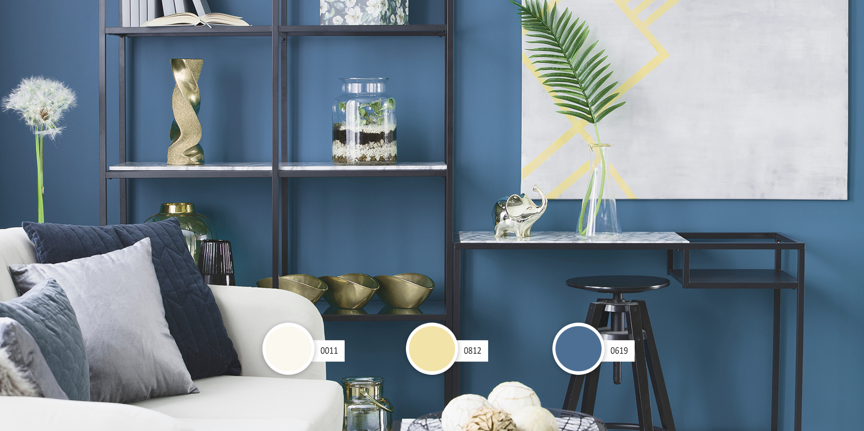 Gold elephant and a leaf in a glass vase placed on marble desk in blue living room interior with decor on metal rack